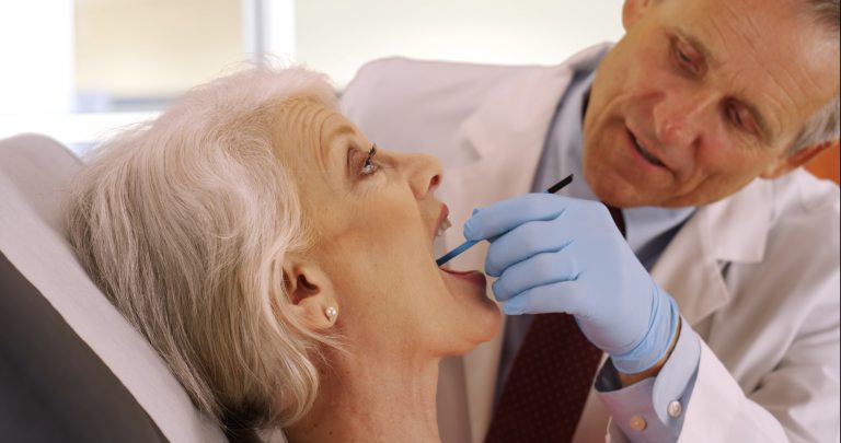 senior dentist examining elderly woman's teeth